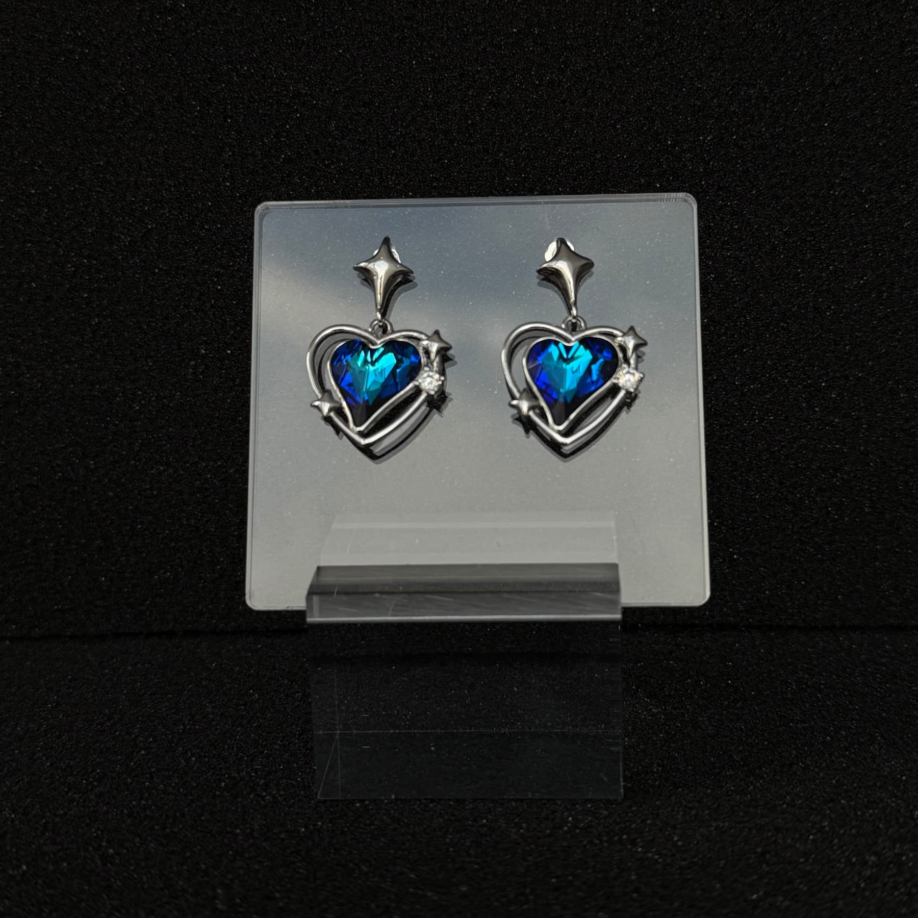 Future Spark's Zephyra Heart Earrings in 'Abyss Core', showcasing a heart-shaped gemstone in a profound deep blue, evoking the mysteries of the ocean depths, set in sleek silver.