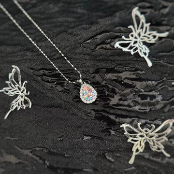 Future Spark's Nyra Teardrop Starburst Necklace featuring a shimmering iridescent teardrop gemstone with a delicate diamond accent, on a silver chain.
