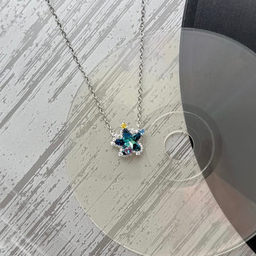 Artistic display of Future Spark's Seren Star Necklace, showcasing its celestial star pendant and sleek silver chain against a textured, mood-lit background to evoke the brand's unique, futuristic aesthetic.