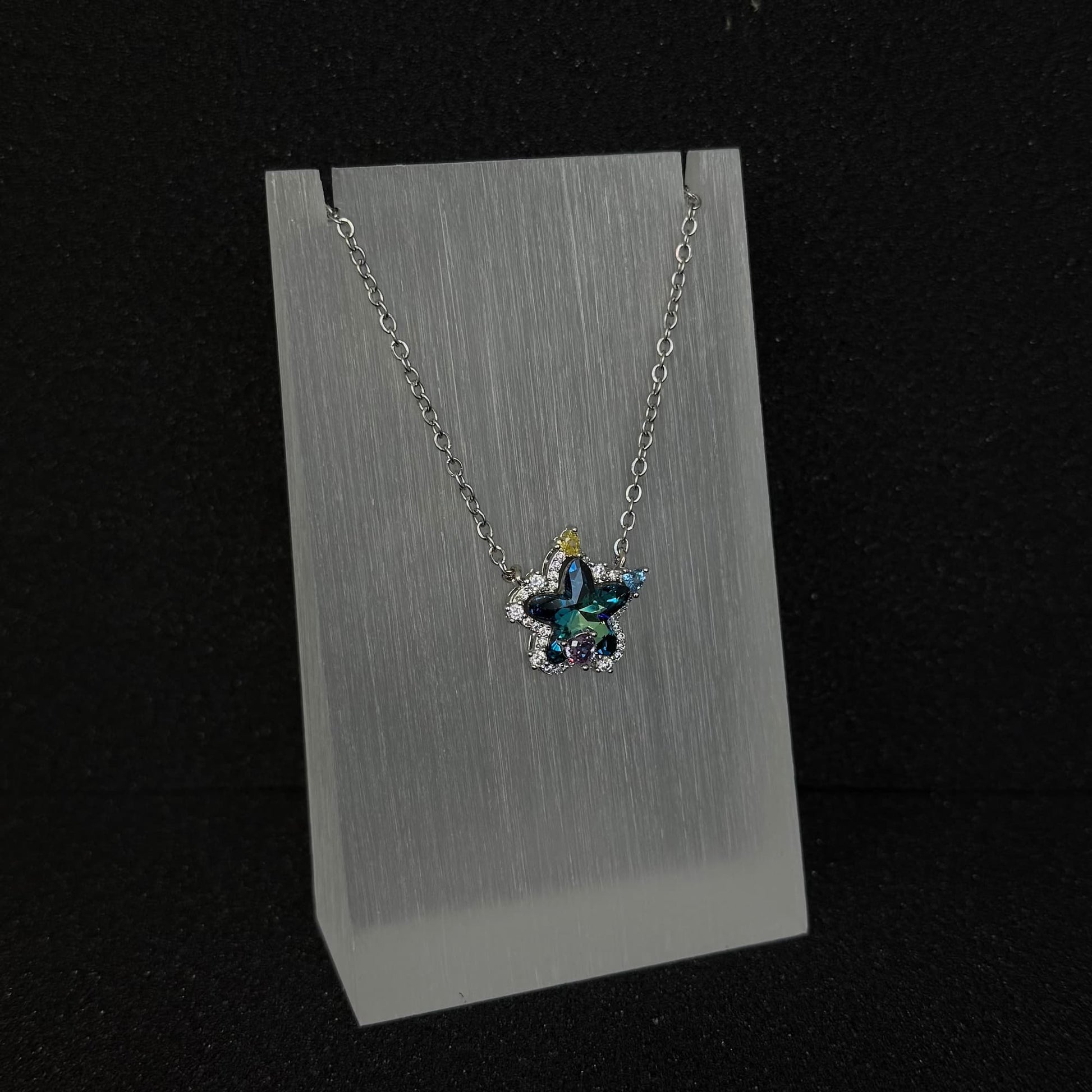 The 'Celestial Trail' variant of Future Spark's Seren Star Necklace, front view, featuring its distinctive gemstone with flowing, multi-tonal hues like a comet's tail, set within the silver star pendant.